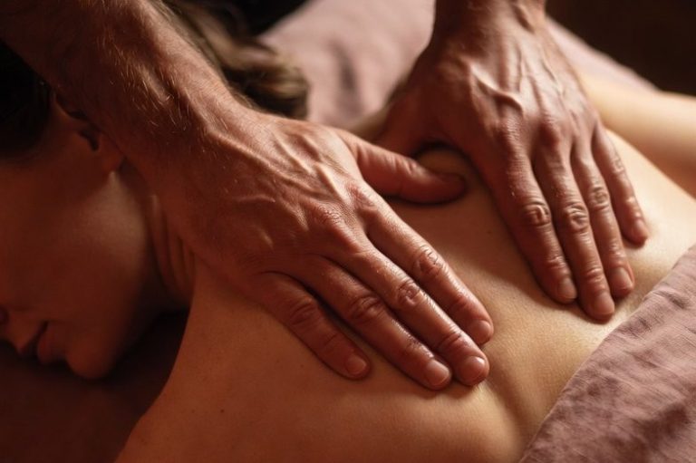 Eine Person erhält eine Rückenmassage mit sanften Händen.