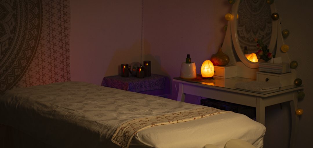 Stimmungsvolles Massagezimmer mit Mandala-Wandteppich, Massageliege und Kerzen bei Hannover Massage