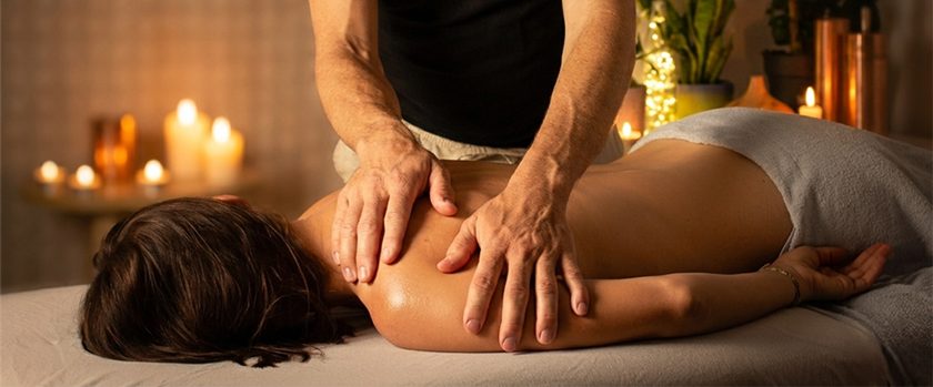 Frauen_Rueckenmassage_Hannover Eine Frau erhält eine Rückenmassage in einem ruhigen, stimmungsvoll beleuchteten Raum.
