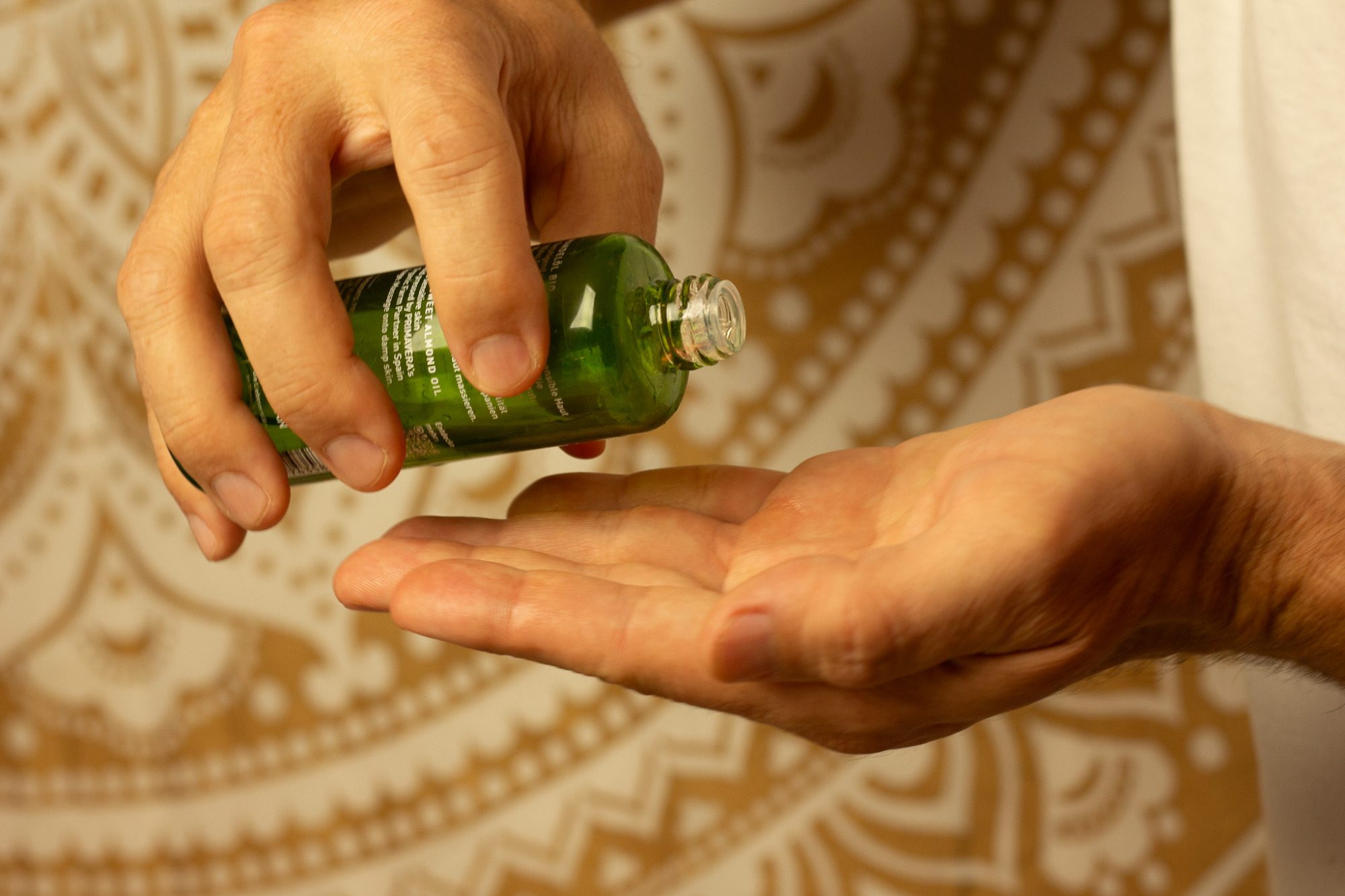 Entspannendes Massagezimmer in warmem Purpurlicht in Hannover mit Mandala-Wandteppich, Massageliege, Salzlampe, Kerzen und duftenden Ölen